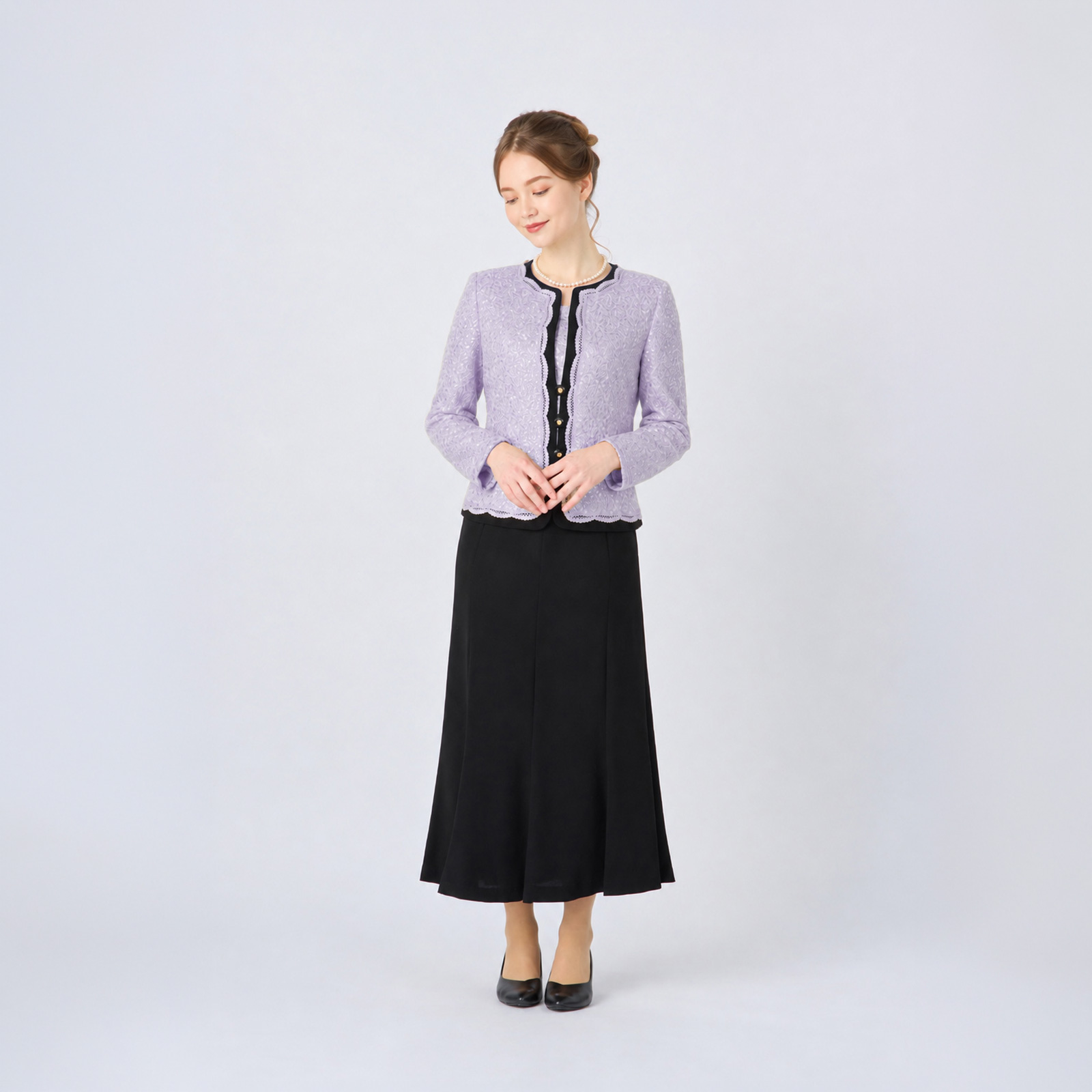ラベンダーのレースジャケットと黒のロングスカートを着用した女性